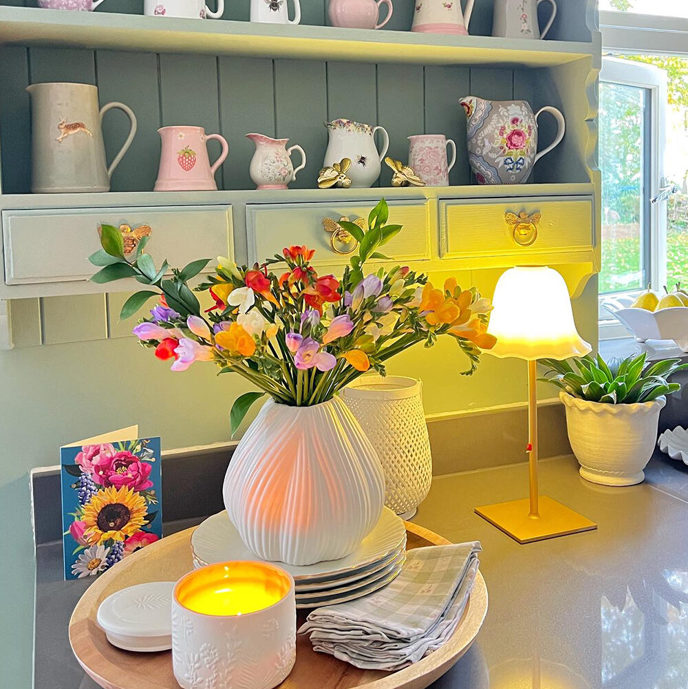 Colourful long stemmed freesia in white vase in kitchen